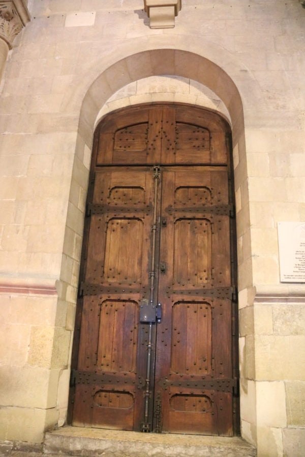 tall arched wooden door in se cathedral lisbon with kids
