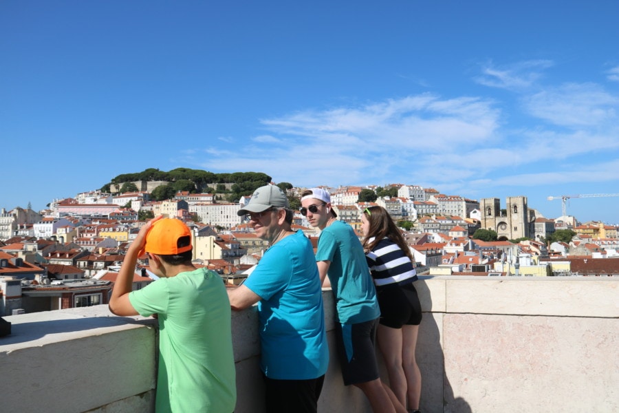 all kids and john looking over edge towards orange roofs of Alfama
