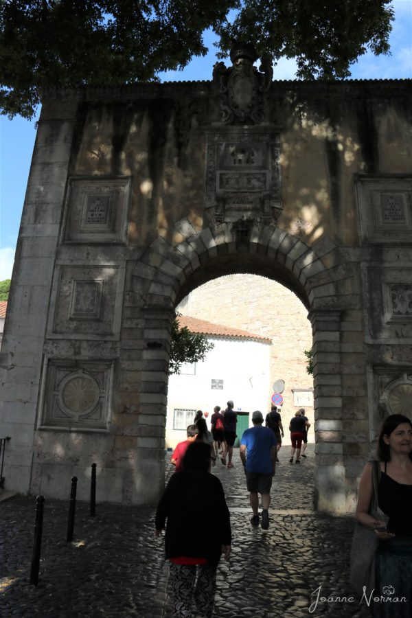 family walking through tall stone archway to Castelo de Sao Jorge in Alfama Lisbon