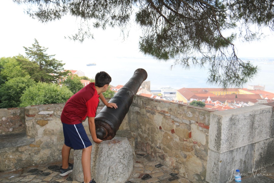 Caiden in red shirt pretending to shoot cannon facing river is fun thing to do in Alfama Lisbon