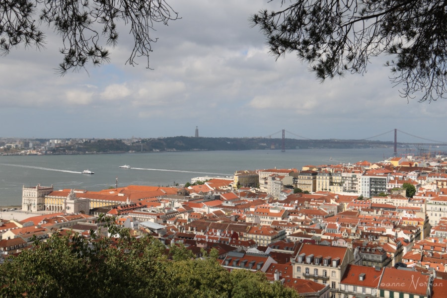 View of Lisbon rooftops and river with bridge and christo rei statue
