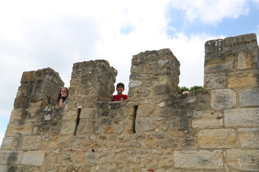 Two kids looking through top of the castle wall in alfama