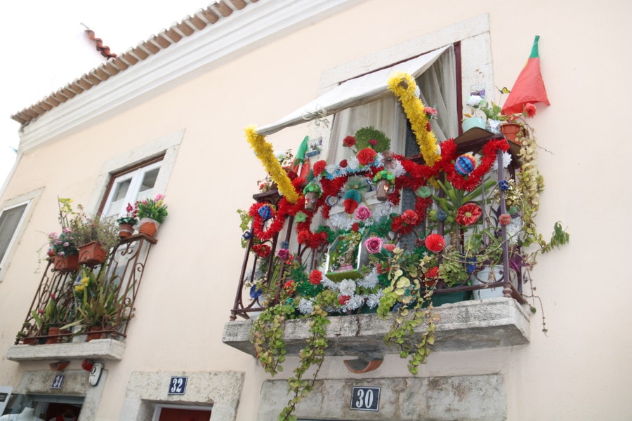 balcony in Alfama with red and yellow garlands perfect for Lisbon Holidays