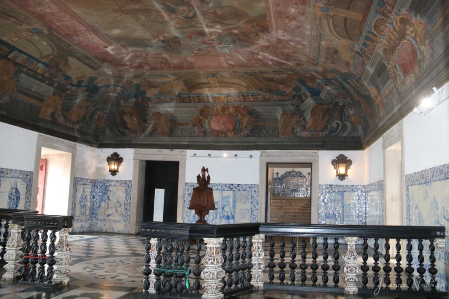 black railing with blue and white tiled walls and painted ceiling in entrance area of Monastery in Alfama