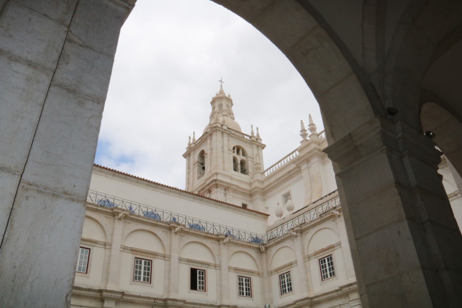 white church peaking out through archway great for Lisbon with kids