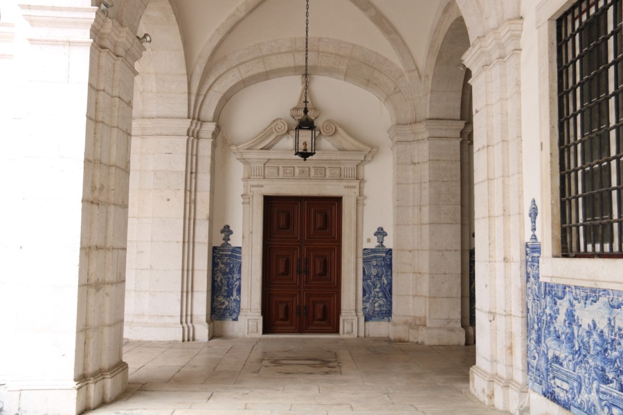 brown wooden door at end of hallway of white marble/stone in Monastery Sao Vicente in Alfama Lisbon with kids