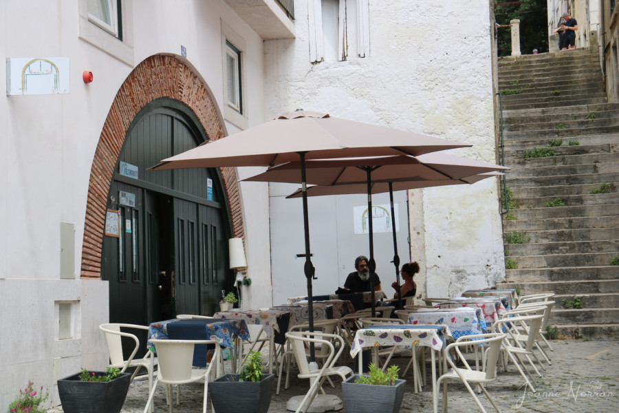 sidewalk cafe with tables and umbrellas and white chairs Beco a Serio