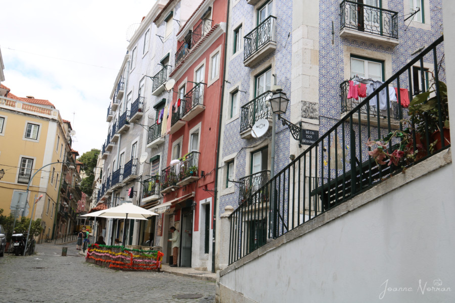 steep narrow street in Alfama Lisbon with tiled houses and blue balconies