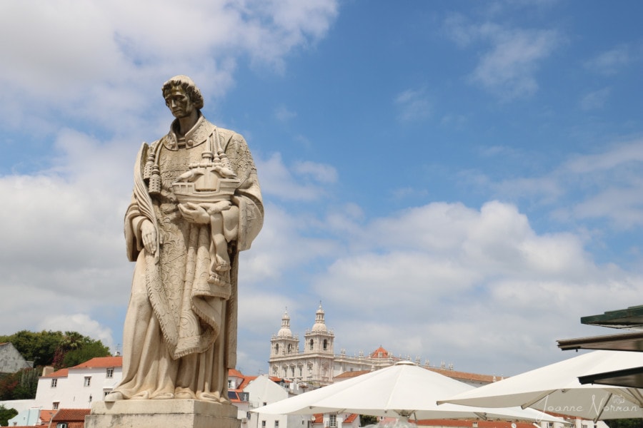 white statue in robes holding sailboat in Alfama Lisbon