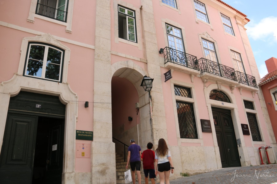 Three kids walking through archway of pink building to reach stairway