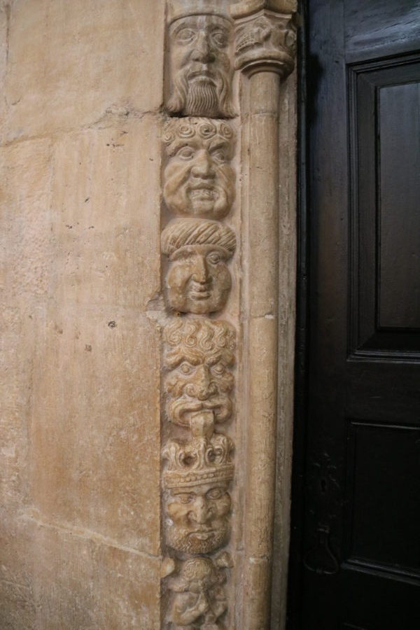 close up of faces carved in stone beside black wooden door is cool thing to do in Belem