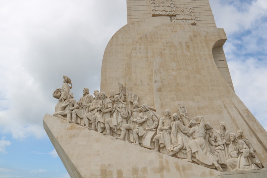 left side of monument of discoveries showing many navigators and explorers in stone carrying different items along boat side is beautiful thing to visit in Belem Lisbon with kids