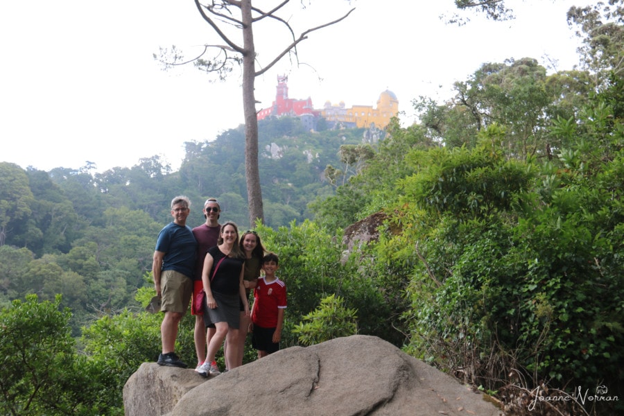 photo of family of five on rock with red and yellow palace behind us