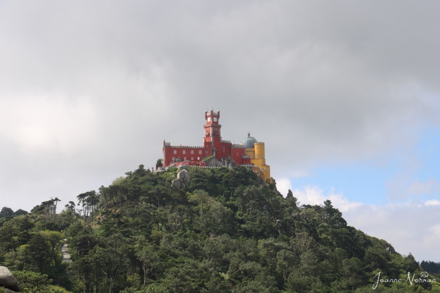 yellow and red Pena Palace on top of green hill on daytrip from Lisbon