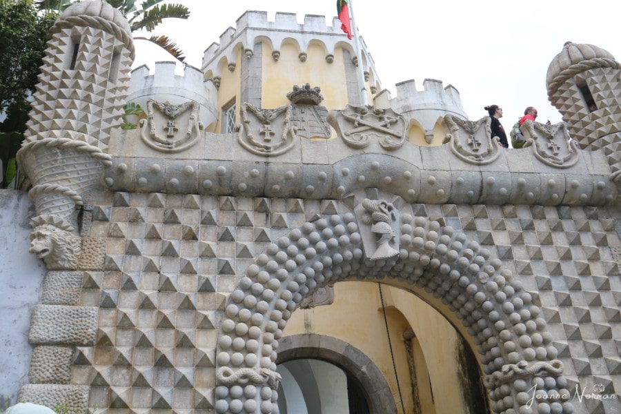 decorative white stone archway entrance with shields along top