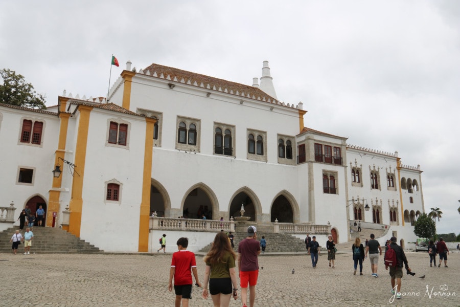 three teens walking towards large white building with yellow arches