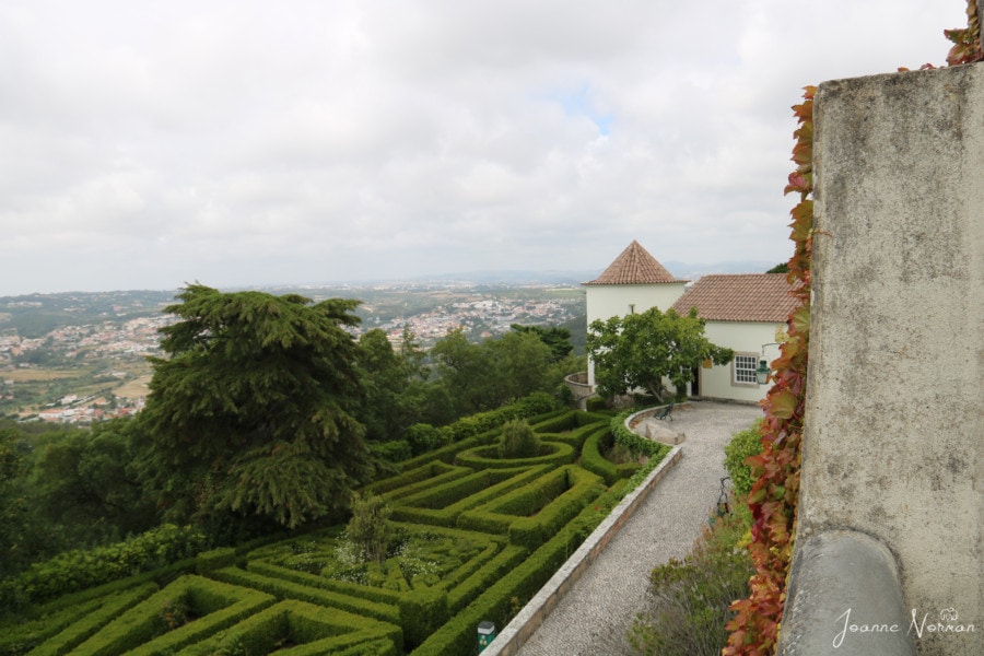 looking over a green hedge maze and white buildings with orange peaks at Tivoli Palacio de Seteais