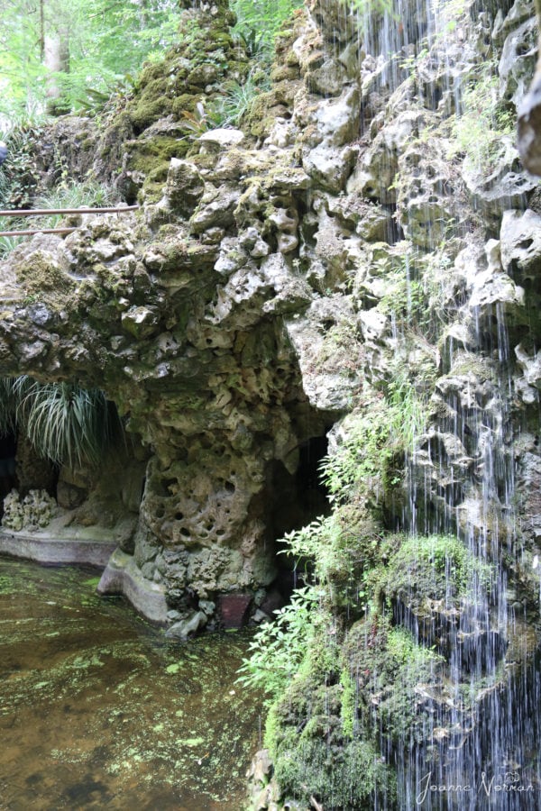 rock tunnel opening with waterfall running in front of it