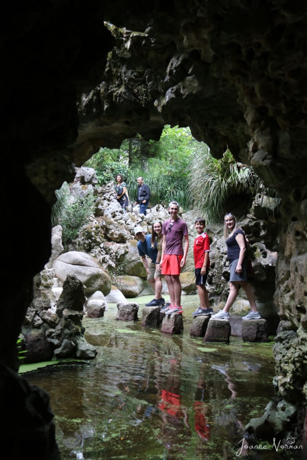 family walking across stepping stones as viewed from stone cave window