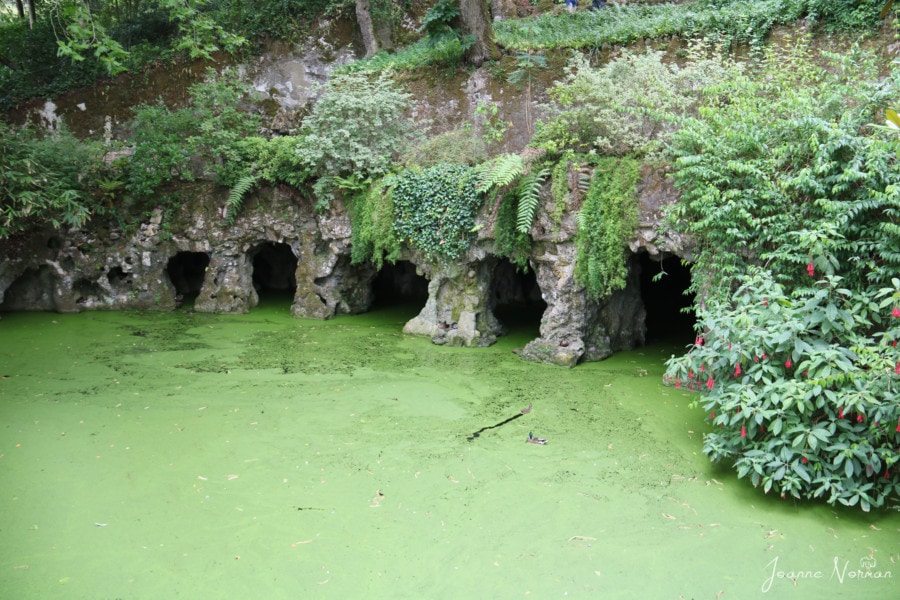 five stone arches over a green lake