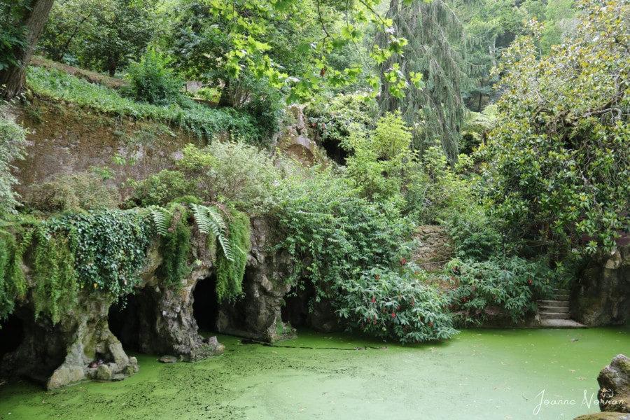 three stone arches over a green lake with flowers