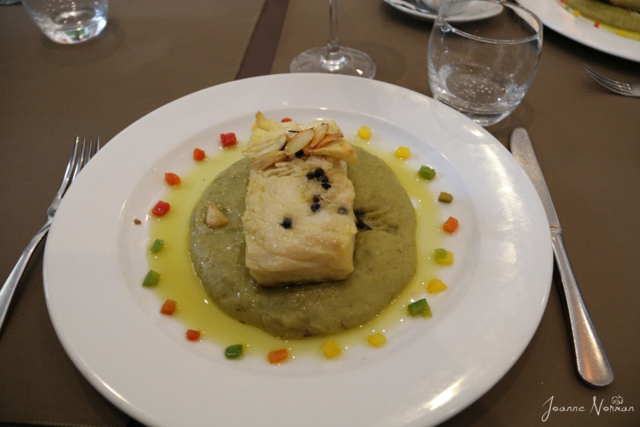 white plate with cod sitting on leek puree and yellow and orange dots around outside at Carmo Restaurant