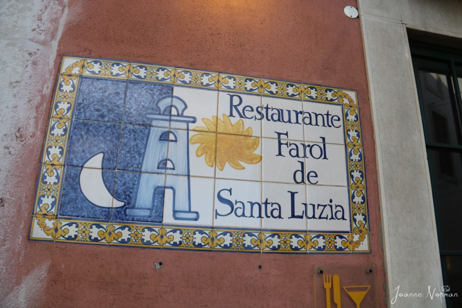 ceramic tile sign of restaurante Farol de Santa Luzia showing lighthouse with yellow sun alfama restaurant
