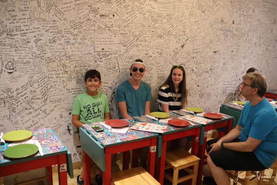 kids sitting at red table with back to wall that is filled with writing in black sharpie at one of best seafood restaurants in Lisbon