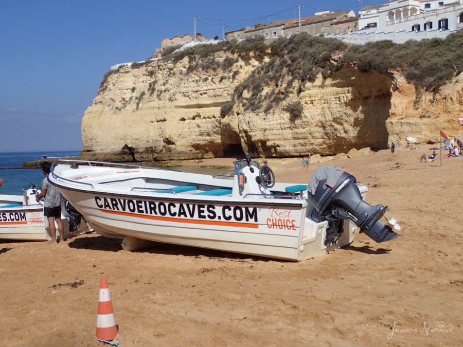 boat with Carvoeiro Caves on side and motor on back sitting on Carvoeiro Beach