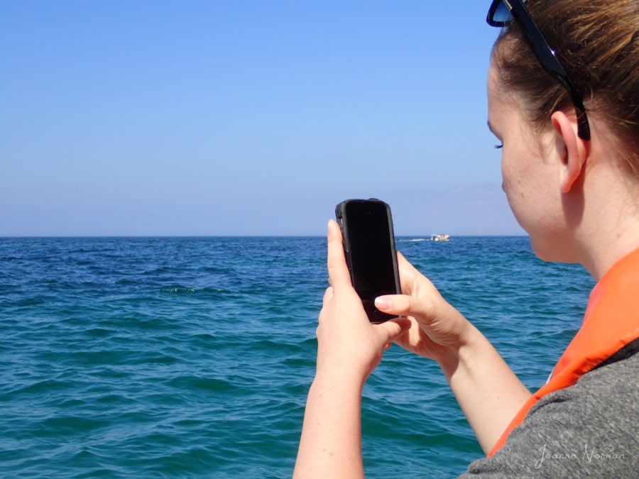 Sydney taking photos with her phone of the ocean