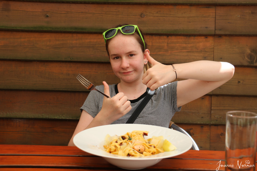 Sydney doing thumbs up next to her pasta bowl great restaurant cesky krumlov