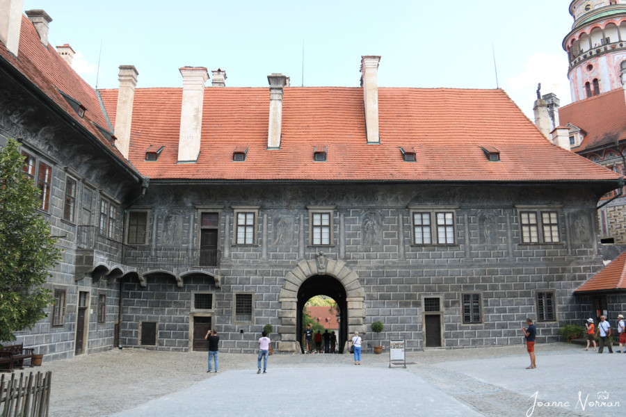 large open space with grey building with orange roof is castle courtyard