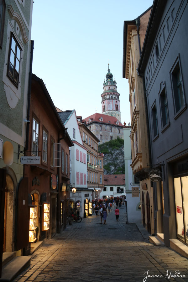castle tower at end of narrow road with colourful houses is cesky krumlov