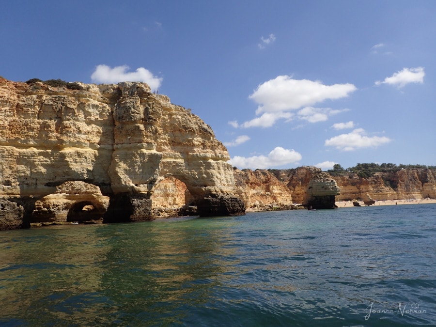 M shaped sandstone rock formation near beach and ocean Praia da Marinha