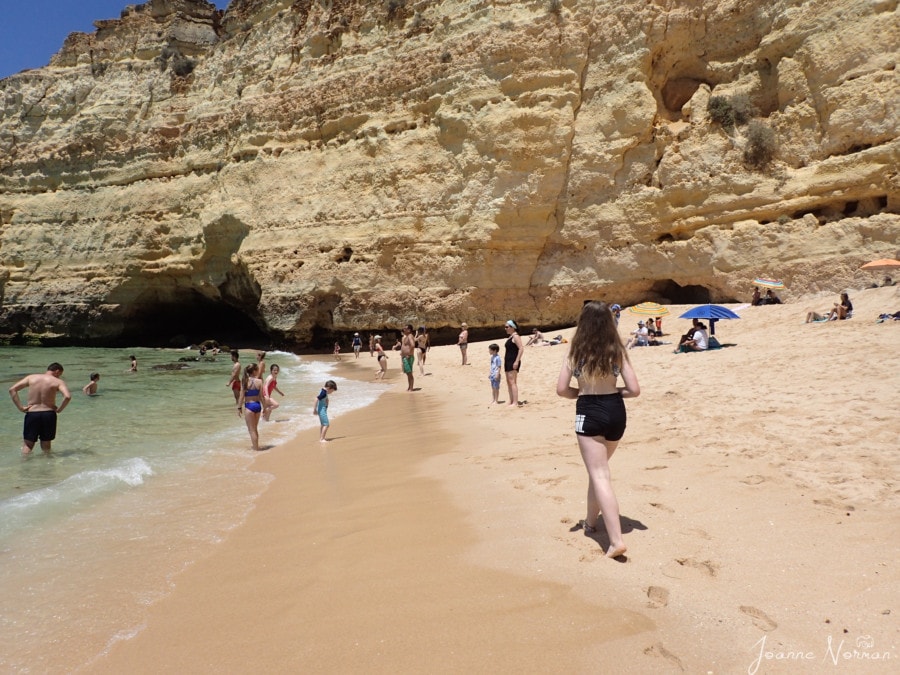 sydney walking down beach with orange stone cliffs along side