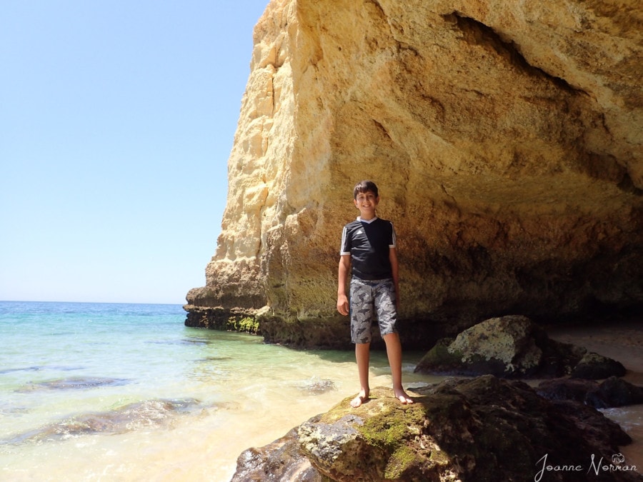 Caiden in front of orange cliff standing on rock at Praia de Vale Centeanes