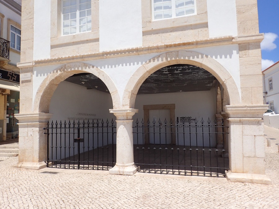arched white and pink trim building with black medal bars is mercado escravos Lagos things to do from Carvoeiro