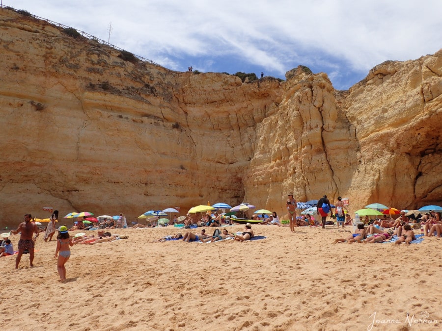 large beach with massive orange cliffs behind at Praia do Carvahlo