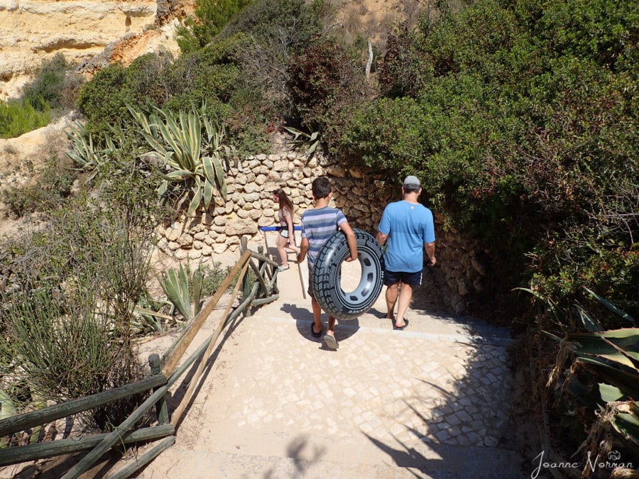 boy holding grey swimming tube and man in blue walking down sandy hill to Praia da Marinha Carvoeiro Algarve