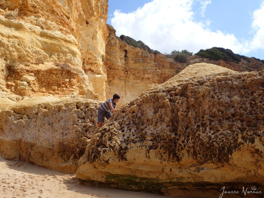 Caiden climbing on large sandstone rock next to cliff on Praia da Marinha is things to do in Carvoeiro