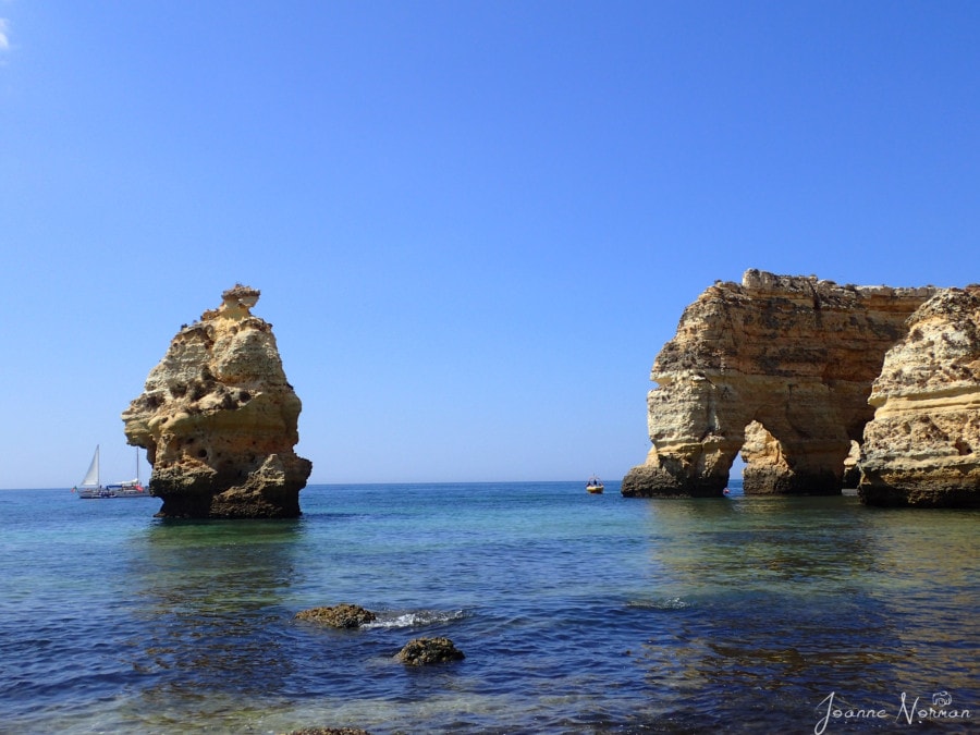 rock formations in water one shaped like large M at Praia da Marinha