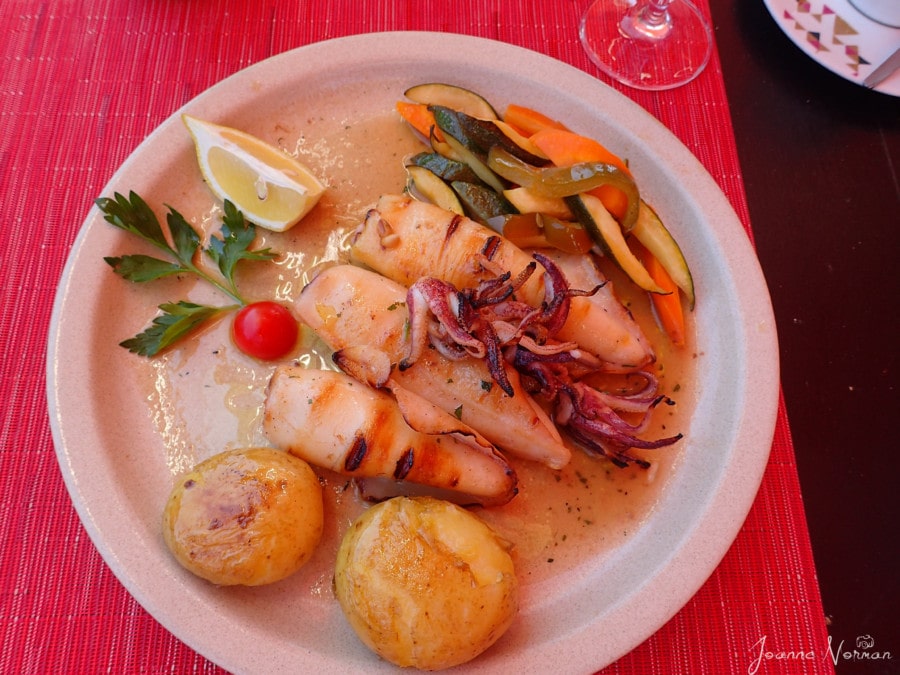 squid with potatos and carrots on white plate and red tablecloth
