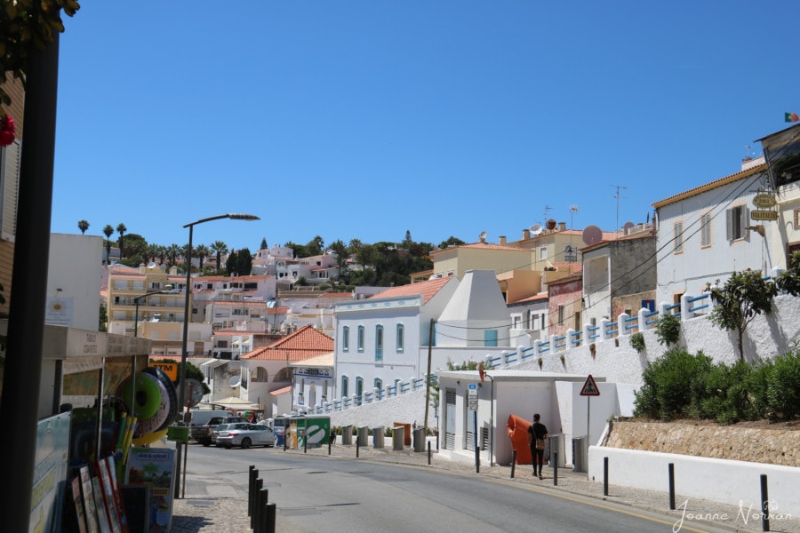 white buildings with orange roofs with road going between  is village of carvoeiro