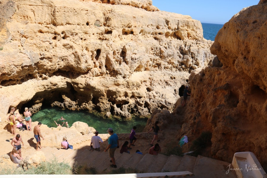 pool of water among sandstone cliffs with people swimming is one of things to do in Carvoeiro Algarve