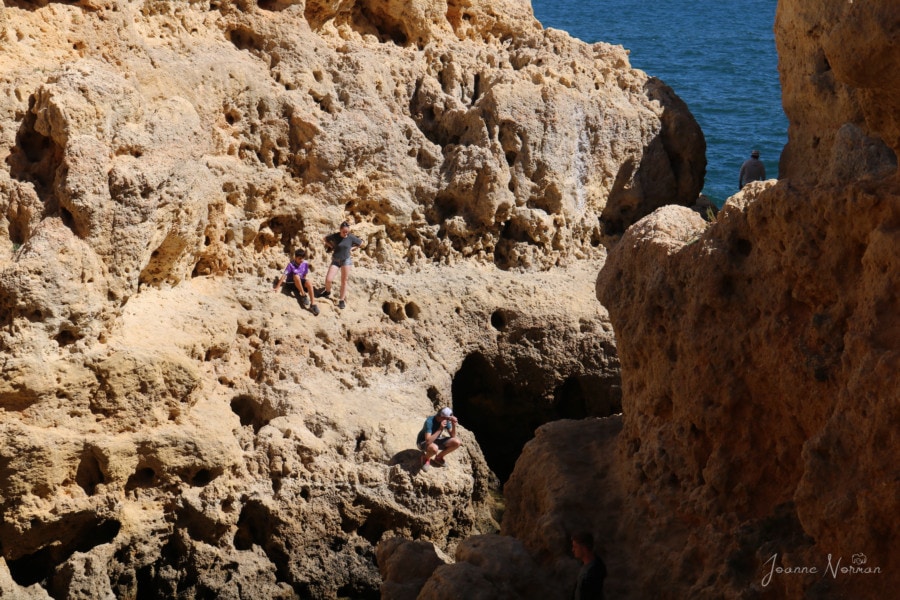 family walking on orange sandstone cliffs next to ocean Algar Seco