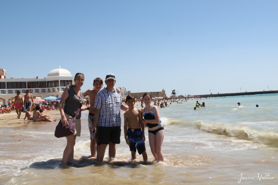 our family on beach with splashing waves is great for family holidays in Spain with kids