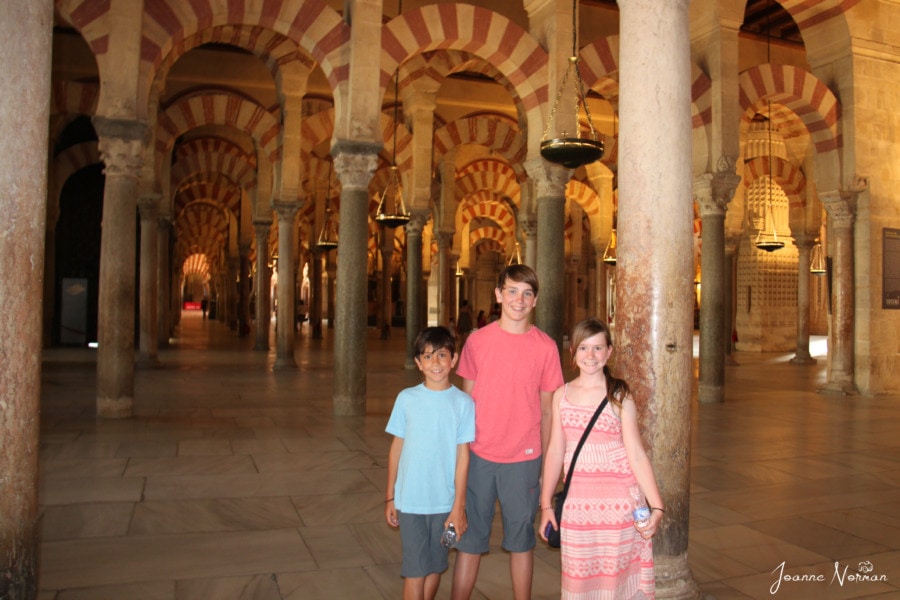 our three kids inside building with aches in red and white during family holidays in Spain