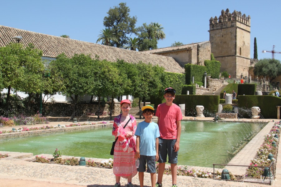 three kids in garden in front of pond during Spain with kids