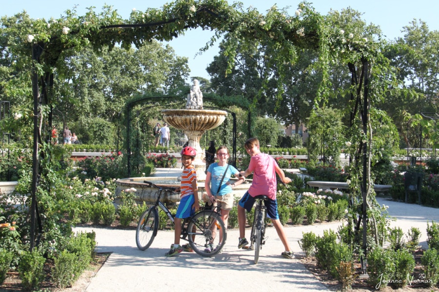 three kids on bike in park with overhanging vines Retiro Park Madrid with kids