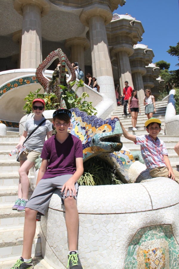 our three kids sitting by colourful iguana on stairway great things to do with kids in Barcelona